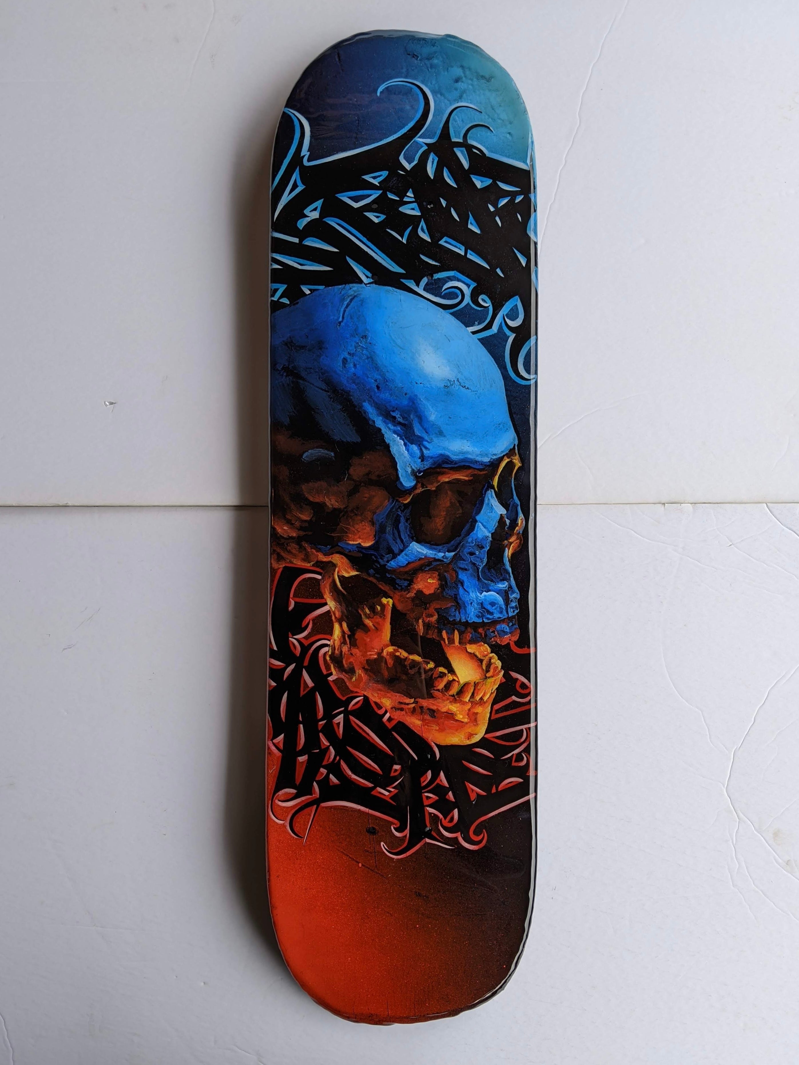 Dramatic lighting skull with Caligraffiti style lettering painted on a skateboard