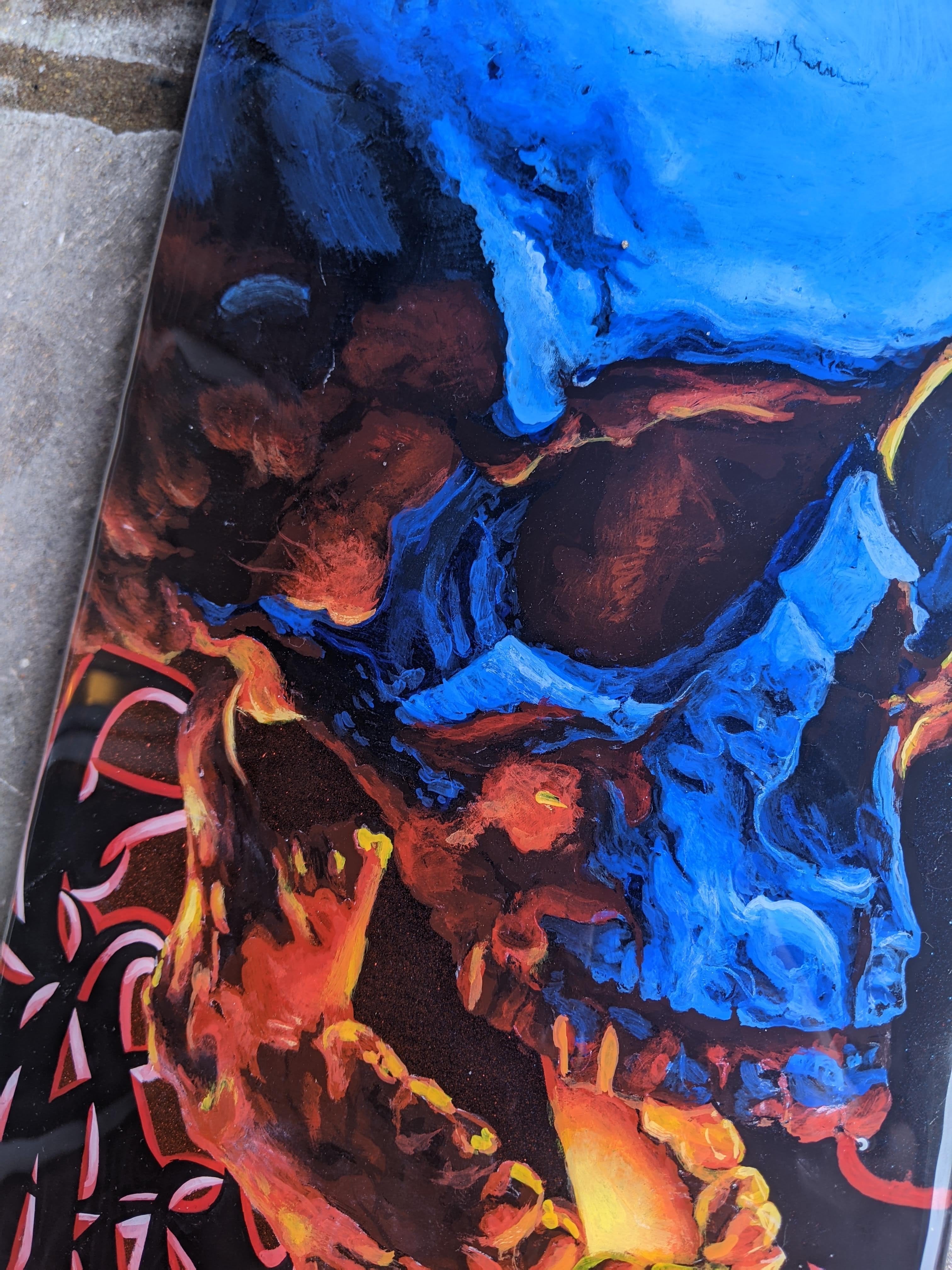 Custom hand-painted skateboard deck by Horus featuring a blue and orange skull with intricate black graffiti lettering and a high-gloss finish.
