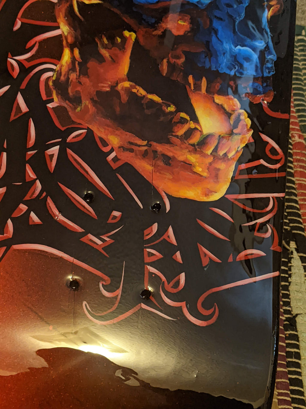 Custom hand-painted skateboard deck by Horus featuring a blue and orange skull with intricate black graffiti lettering and a high-gloss finish.
