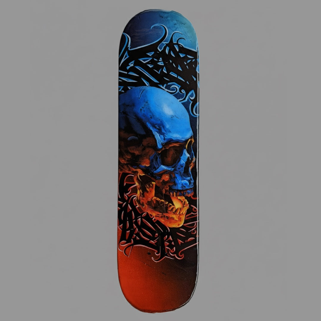The underside of a skateboard deck showcasing custom artwork by Horus. The design features a large, realistic human skull painted with a striking gradient—icy blue at the top transitioning to fiery orange and red at the bottom—set against a dark background with intricate black script and tendrils.